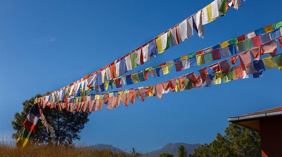 Colorful Tibetan prayer flags stretching across a bright blue sky.
