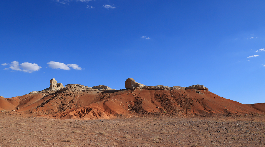 Red rock cliffs under blue sky in Gobi Desert.