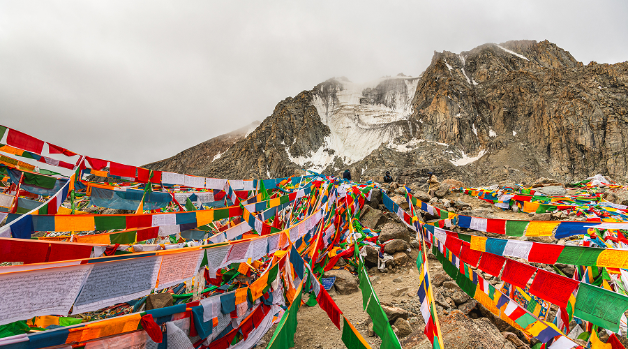 Colorful prayer flags strung across a rocky Tibetan pass.