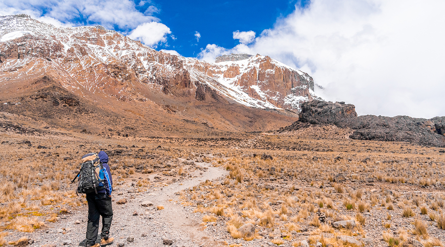 Backpacker hiking on a trail toward a sacred Tibetan mountain.