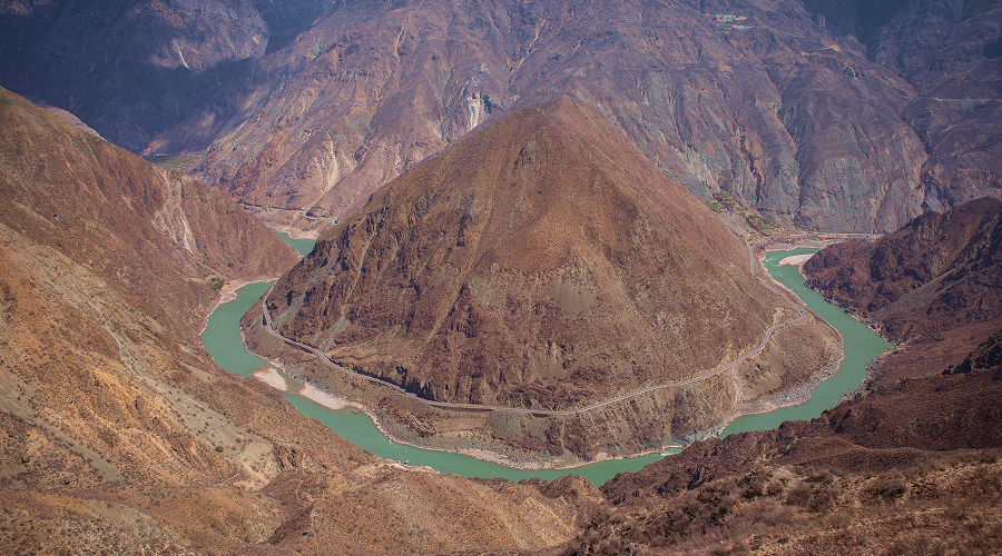 Dramatic horseshoe bend of a river cutting through mountain valleys.