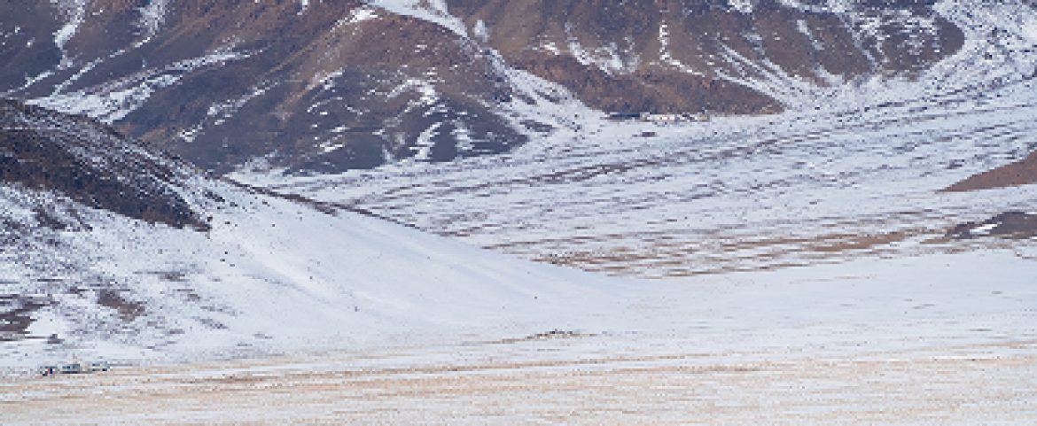 Horse riders traversing vast snow-covered Mongolian steppe landscape.