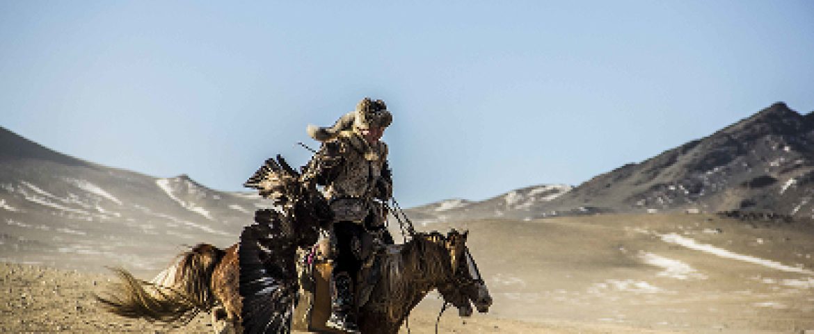 Young eagle hunter galloping through Golden Eagle Festival in Mongolia.