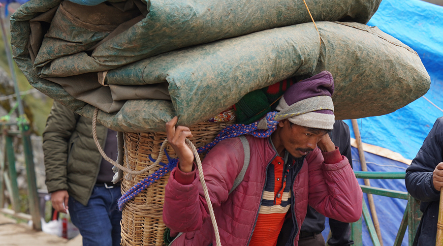 Porter carrying large canvas bundle on a mountain expedition