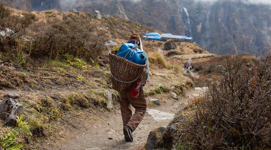 Porter transporting supplies in traditional basket on mountain trail