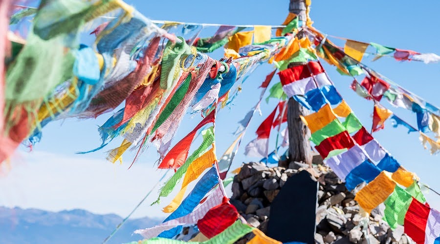 Traditional Tibetan prayer flags tied to a mountain shrine.