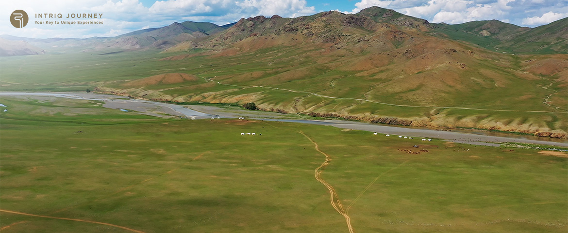 Aerial view of green grasslands river and yurt camps.